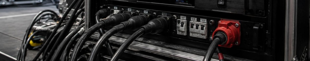 Backstage-Rack mit Power Conditioner, Spannungsstabilisator, Stromverteilung und vielen angeschlossenen Kabeln für eine sichere Live-PA-Stromversorgung.